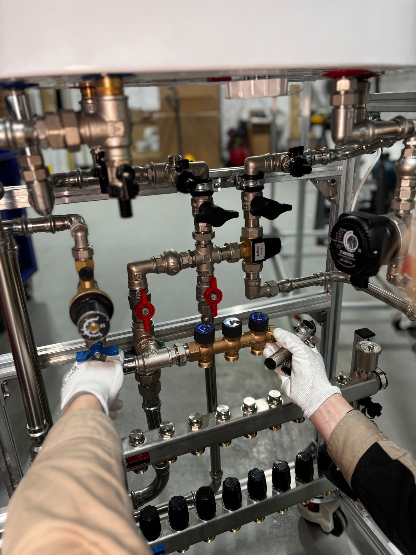 Engineer in white gloves working through the valves on a heating pipework manifold