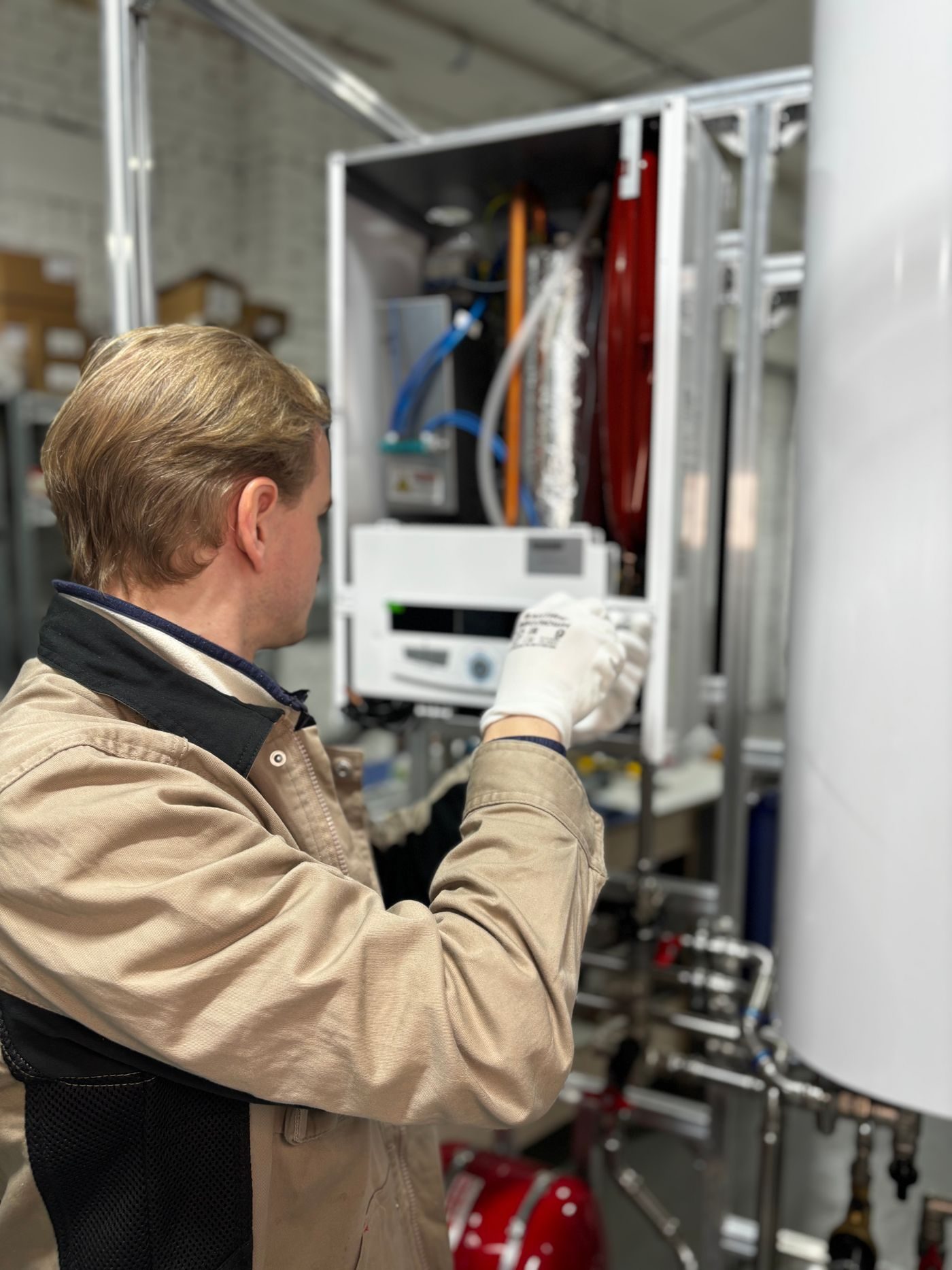Engineer checking the control panel of a combi boiler with the front off