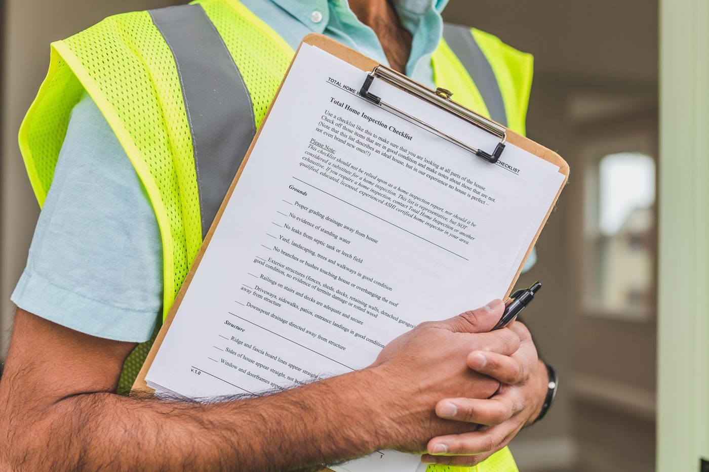Close-up of hands holding a checklist on a clipboard with a pen